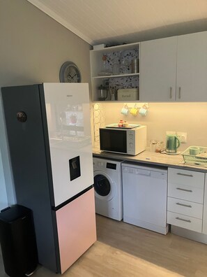 A compact kitchen with a refrigerator, microwave, washing machine, and a sink. - Superb 2-bedroom cottage in charming Stellenbosch for your getaway (Stellenbosch)