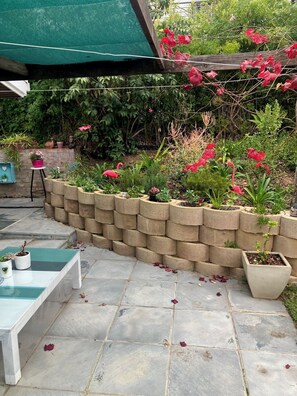 A garden with a stone wall, potted plants, and a bench. - Superb 2-bedroom cottage in charming Stellenbosch for your getaway (Stellenbosch)
