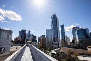 Eine Skyline mit modernen Hochhäusern, blauem Himmel und einer Fußgängerbrücke.