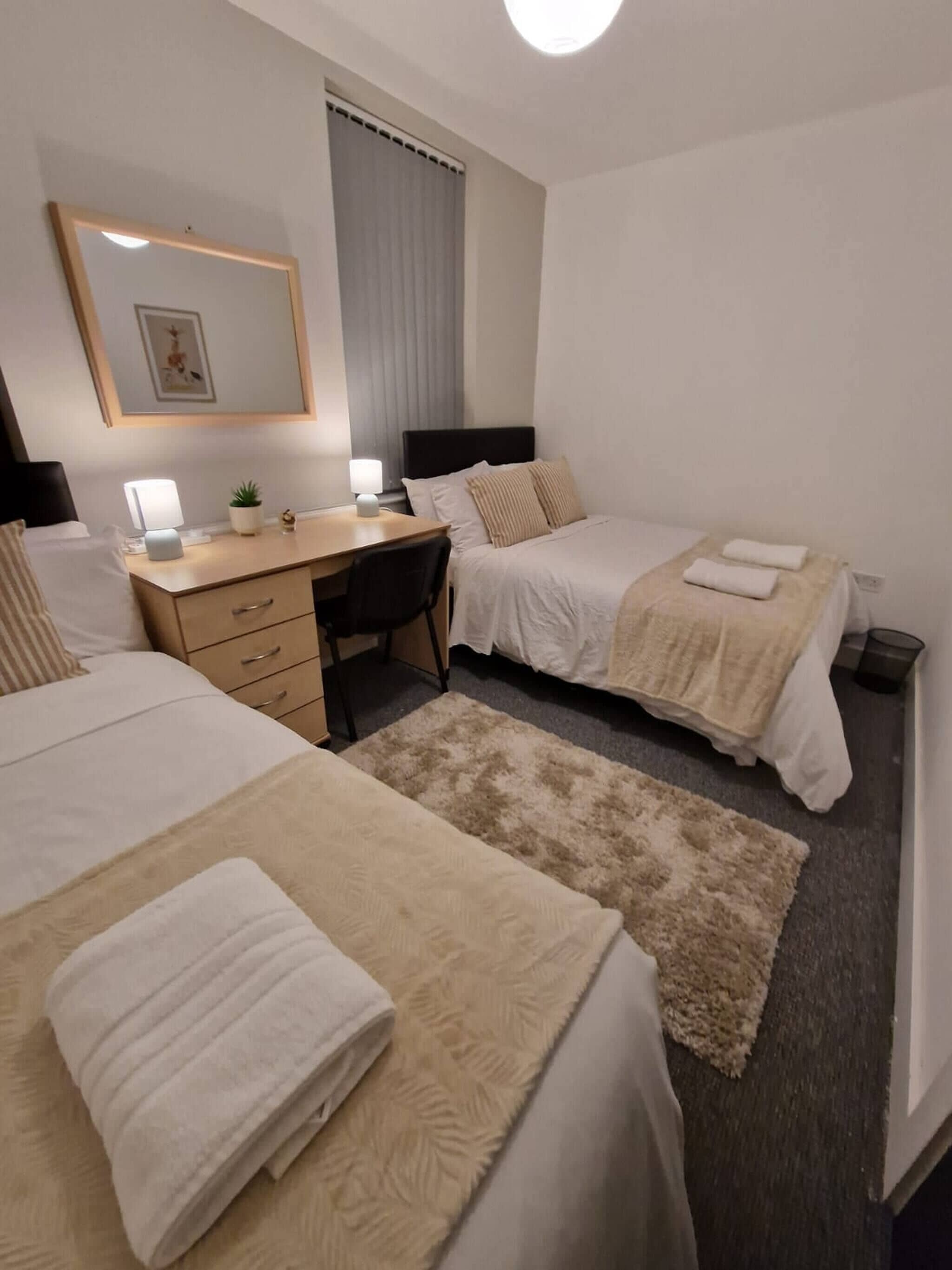 A hotel room with two beds, a desk, and a chair.