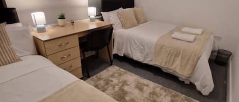 A hotel room with two beds, a desk, and a chair.