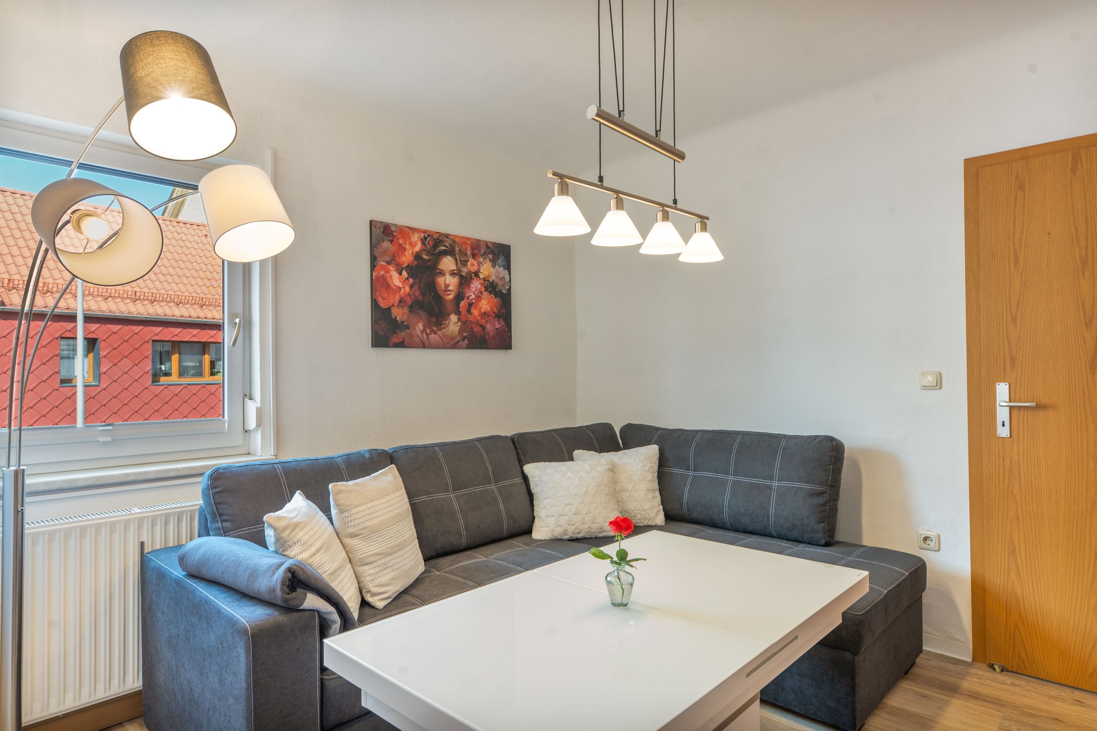 En moderne stue med en sofa, et hvidt bord og et billede på væggen.
