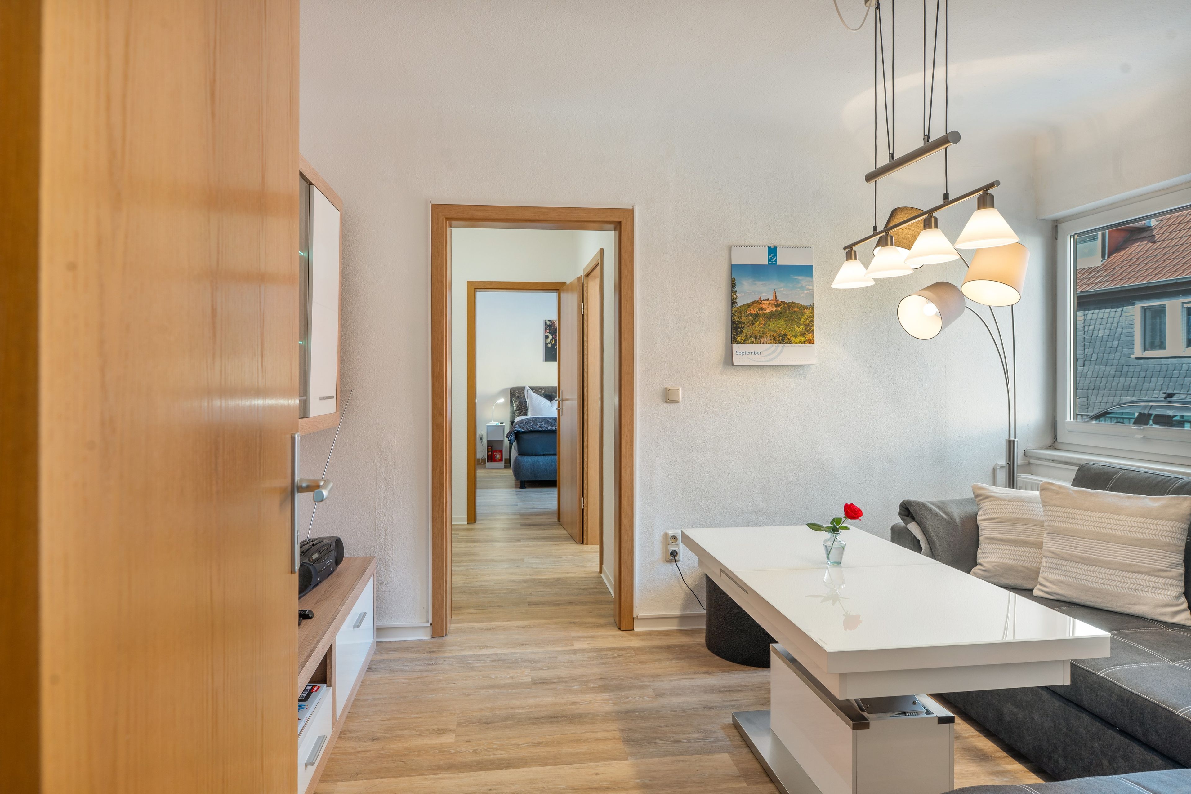 Una cocina moderna con un mueble de madera, una encimera blanca y una zona de comedor con mesa y banco.