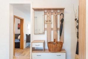 Ein Zimmer mit einer Holzbänke, einem Korbwannenkorb, einem Spiegel und einem Kleiderständer.