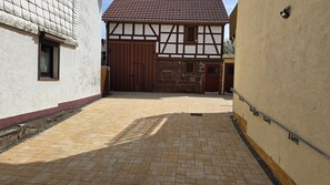 Ein Innenhof mit einem traditionellen Fachwerkhäuschen, einem ehrwürdigen Eingangstor und einem gepflasterten Weg.