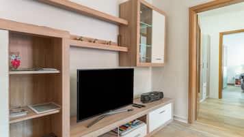 Un soggiorno moderno con una televisione a schermo piatto, scaffali in legno e una radio.
