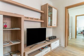 A modern living room with a flat-screen TV, wooden shelving, and a radio.