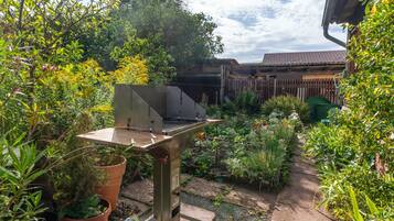 Ein Terrassenbereich mit Grill, Topfpflanzen und Holzzaun.