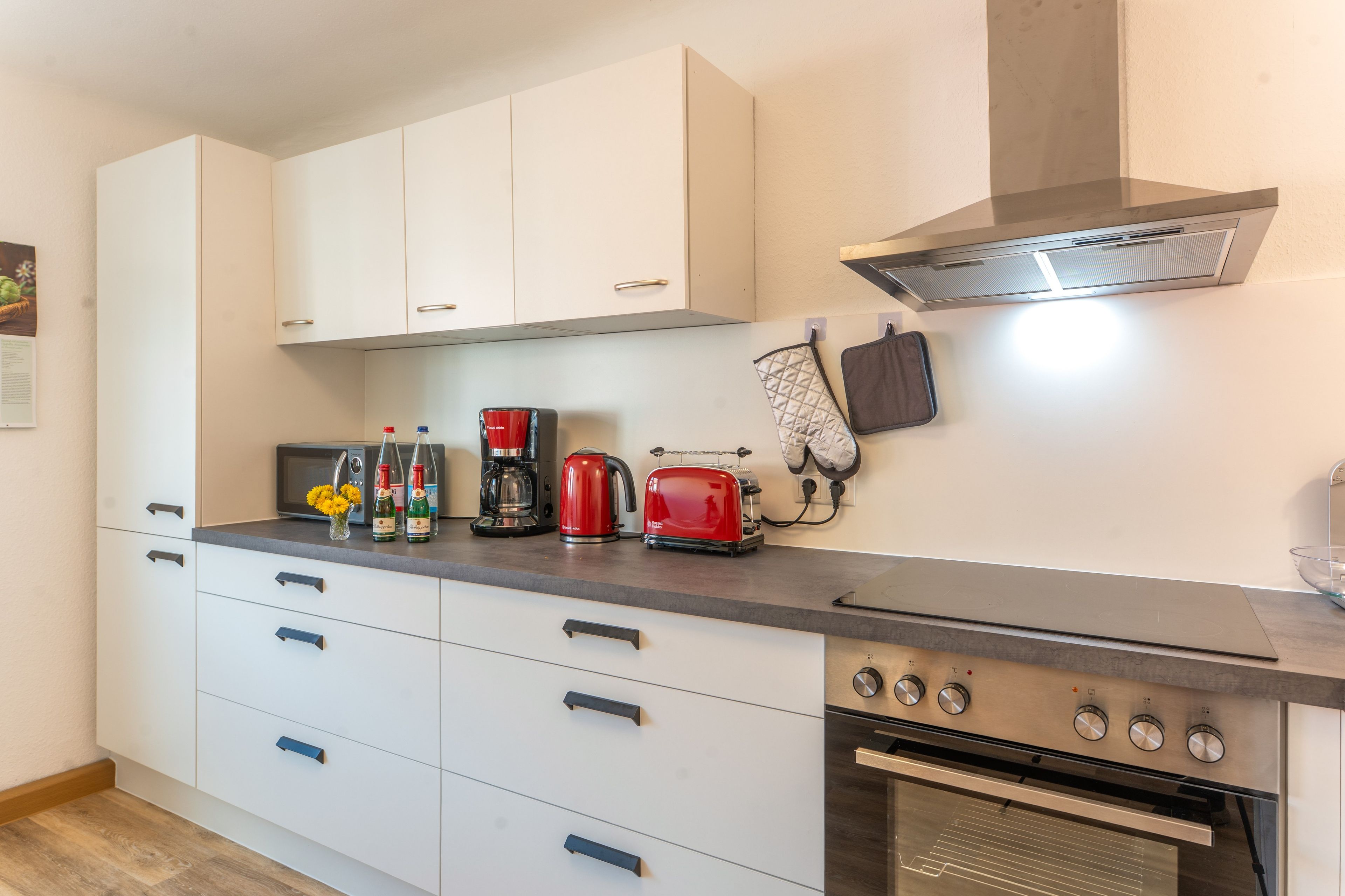 A kitchen with white cabinets, a stainless steel range, a toaster, and a kettle.
