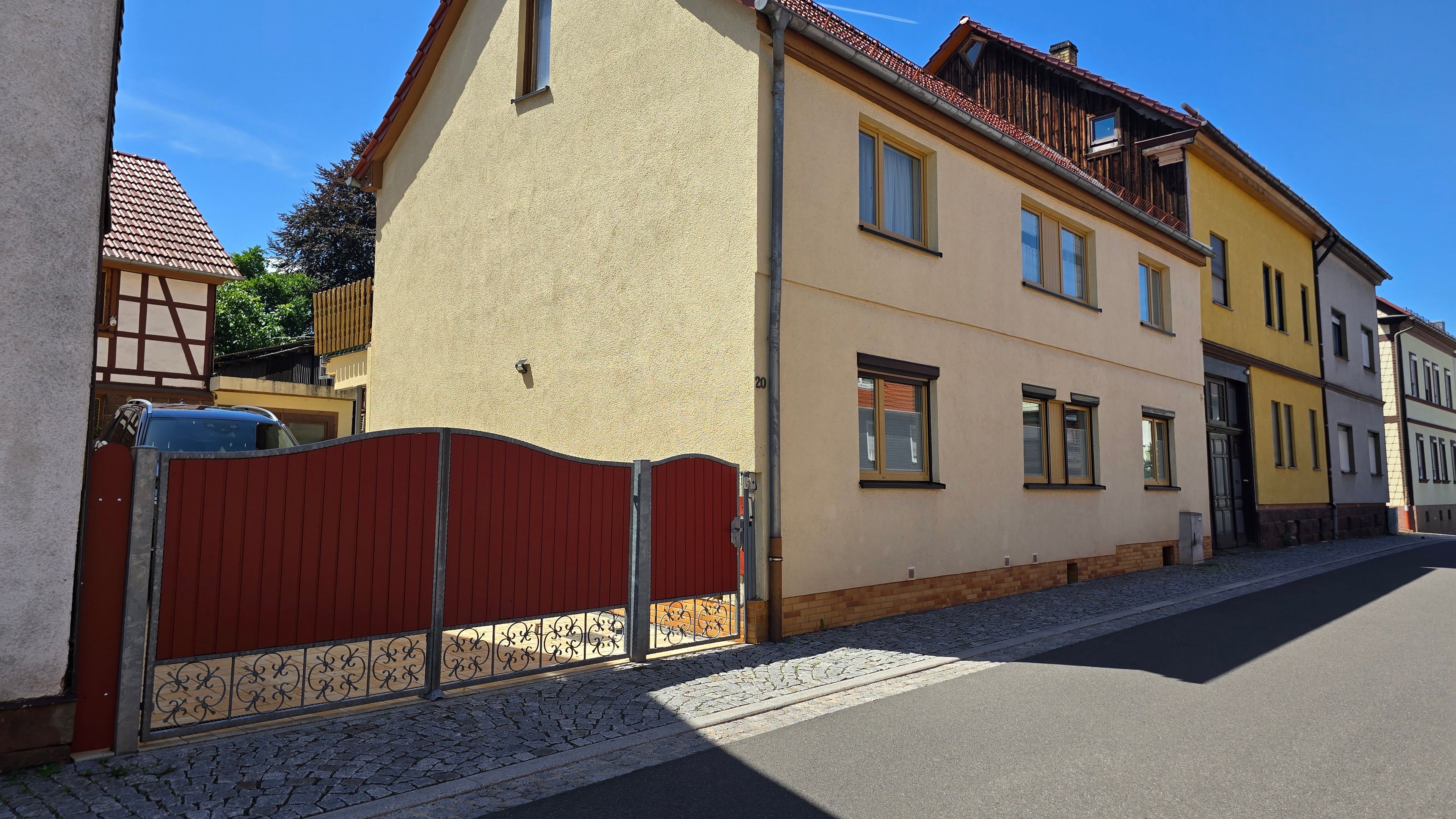 Eine Straße mit Gebäuden, einem roten Tor und Kopfsteinpflaster.