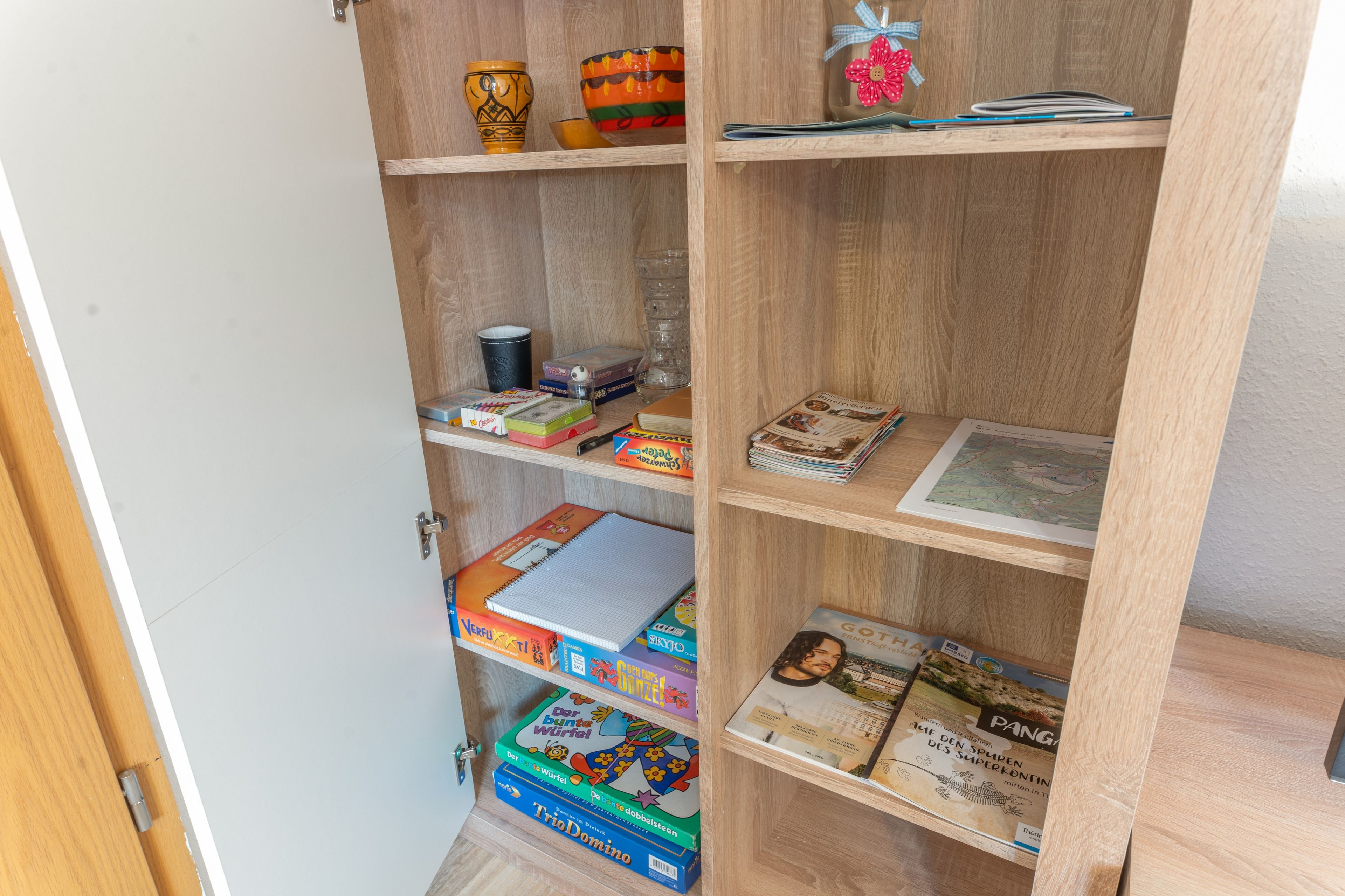 Una estantería de madera con varios objetos, incluyendo libros, un globo terráqueo y adornos.