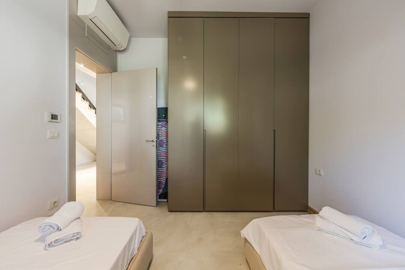 Un dormitorio con dos camas, un armario y una escalera que sube a un piso superior.