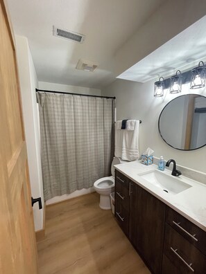 A bathroom with a toilet, sink, mirror, and shower curtain.