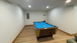 Una mesa de billar en una habitación con suelo de madera y paredes blancas.