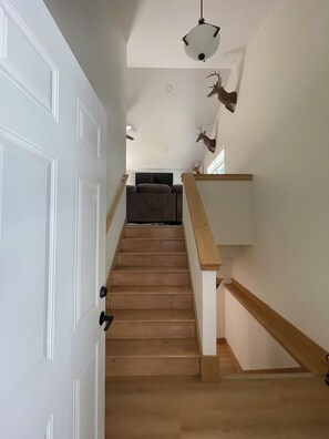 A staircase with wooden steps and a white door on the left. - Welcome to Harrietta Pines – Your Cozy Up-North Family Getaway! (Harrietta)