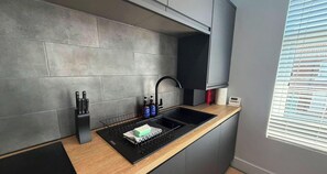 A modern kitchen with a black sink, a knife block, and a bottle of hand soap. - Karpa Coastal Retreat (Fleetwood)