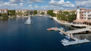 Um hotel à beira-mar com uma fonte central, barcos atracados e uma ponte que liga aos edifícios.