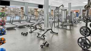Academia com esteiras, aparelhos de musculação e pesos livres.