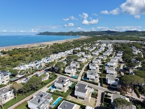 A coastal residential area with modern houses, a beach, and a mountainous backdrop. - Beachside Apartment 307 (Gjiri Lalzit)