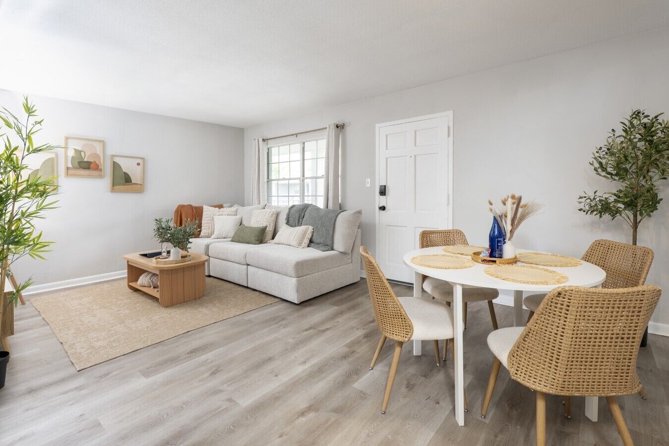 Een woonkamer met een bank, salontafel, eettafel met stoelen en een deur.
