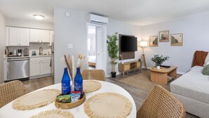 A modern living space with a kitchen, dining area, and a TV. - Cozy 1BR Hideaway w/ FREE Parking · Prime Location (Tampa)