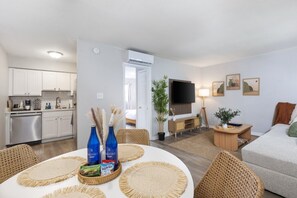 Ein zeitgemäßer Wohnraum mit Küche, Essbereich und Fernseher.