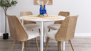 A dining area with a round table, wicker chairs, a potted plant, and a wall-mounted light fixture. - Cozy 1BR Hideaway w/ FREE Parking · Prime Location (Tampa)