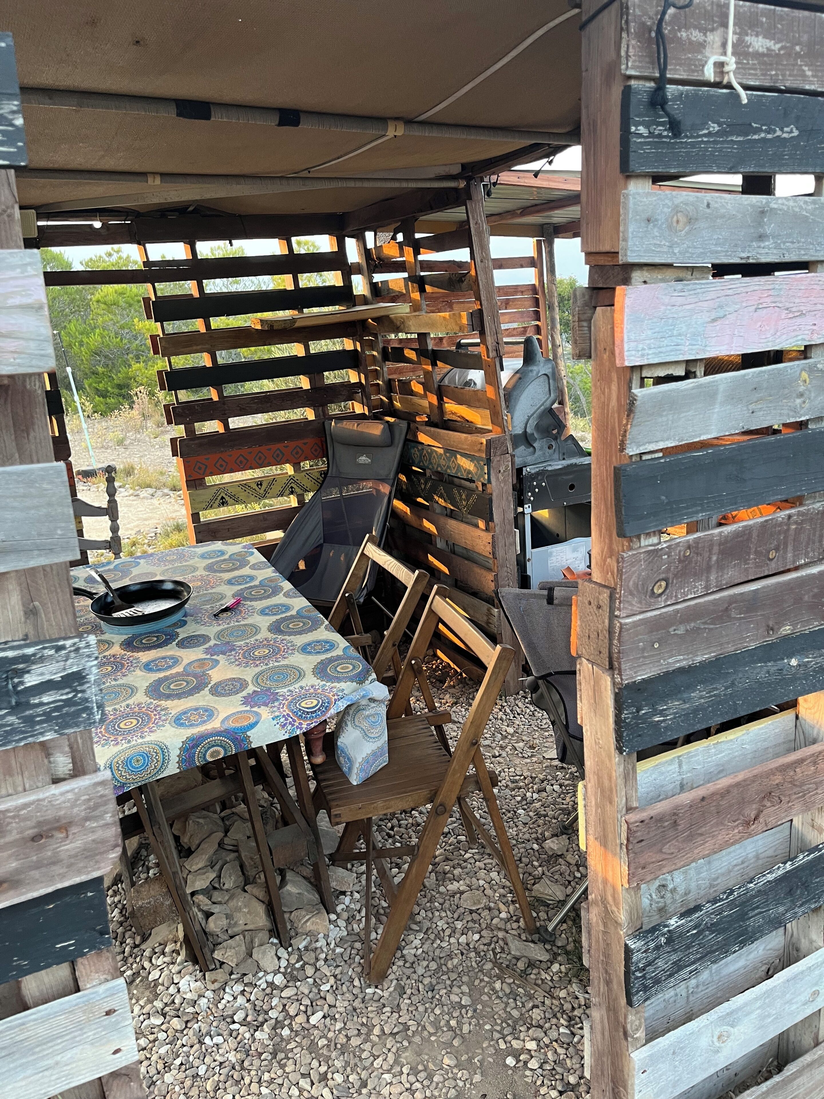 Un espacio al aire libre rústico con una mesa, sillas y una parrilla.