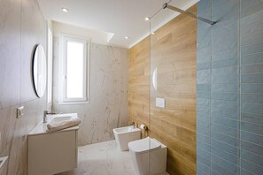 A bathroom with a marble vanity, a toilet, and a shower area. - Villa Selene by Villa Plus (Marzamemi)