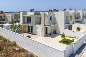 Un immeuble résidentiel moderne doté de nombreux balcons, d’une piscine et offrant une vue dégagée sur les environs.