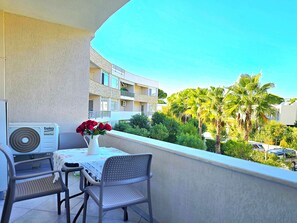 A balcony with a table, chairs, a vase of red roses, and an air conditioning unit. - Lura 2 Holiday Homes 181 (Gjiri Lalzit)