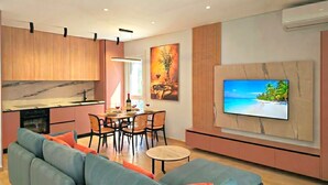 Una sala de estar moderna con un sofá, una mesa de comedor y un televisor montado en la pared.