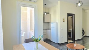 Et moderne køkken med et køleskab, et spisebord med en vase og et lille rundt bord.
