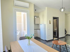 Eine moderne Küche mit Kühlschrank, einem Esstisch mit einer Vase und einem kleinen runden Tisch.