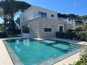 Ein modernes, zweistöckiges Haus mit einem Schwimmbad im Vordergrund.