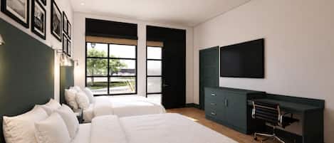 Un dormitorio moderno con dos camas, un escritorio, una silla, un televisor y un ventanal grande.