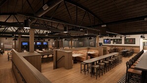 Um restaurante amplo com pé-direito alto, várias áreas de estar incluindo cabines e mesas, e um bar com balcão.