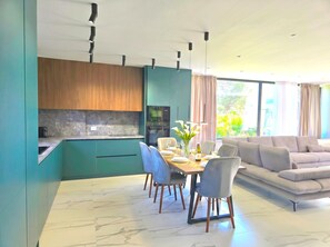 Eine moderne Küche mit Einbauofen und Mikrowelle, ein Essbereich mit Tisch für zwei Personen und ein Wohnzimmer mit Sofa.