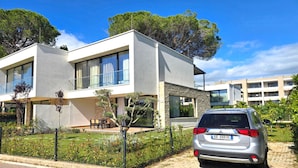 Uma casa moderna de dois andares com um carro estacionado na entrada.