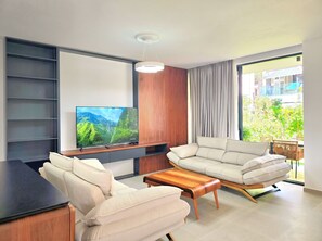 Ein modernes Wohnzimmer mit Flachbildfernseher, Sofa, Couchtisch und Blick auf Grünfläche.