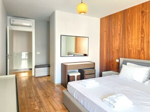 Ein Hotelzimmer mit Bett, Nachttischen, einem Spiegel, einem Kleiderschrank und einem Badezimmer mit Dusche.