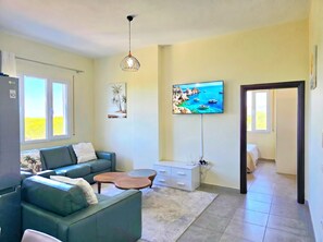 Ein Wohnzimmer mit Sofa, Couchtisch, Fernseher und Bildern an der Wand.