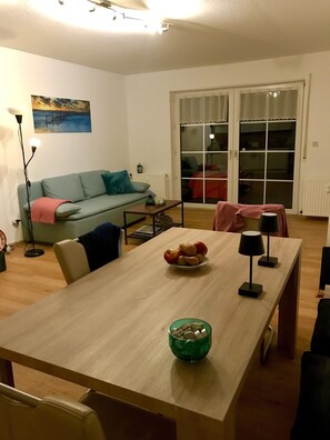 Ein Essbereich mit Tisch, Stühlen, einer Obstschale und einer Stehlampe.