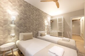 Ein Hotelzimmer mit zwei Betten, einem Kleiderschrank, einem Spiegel und einem Deckenventilator.