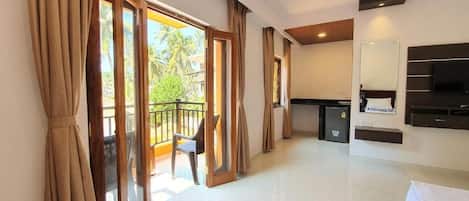 A hotel room with a balcony, a TV, and a bed.