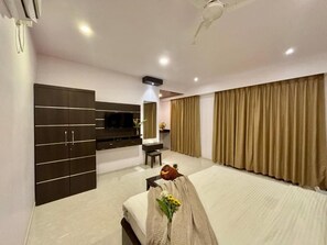 A hotel room with a bed, a TV, a wardrobe, and a ceiling fan. - Casa de Laura (Calangute)