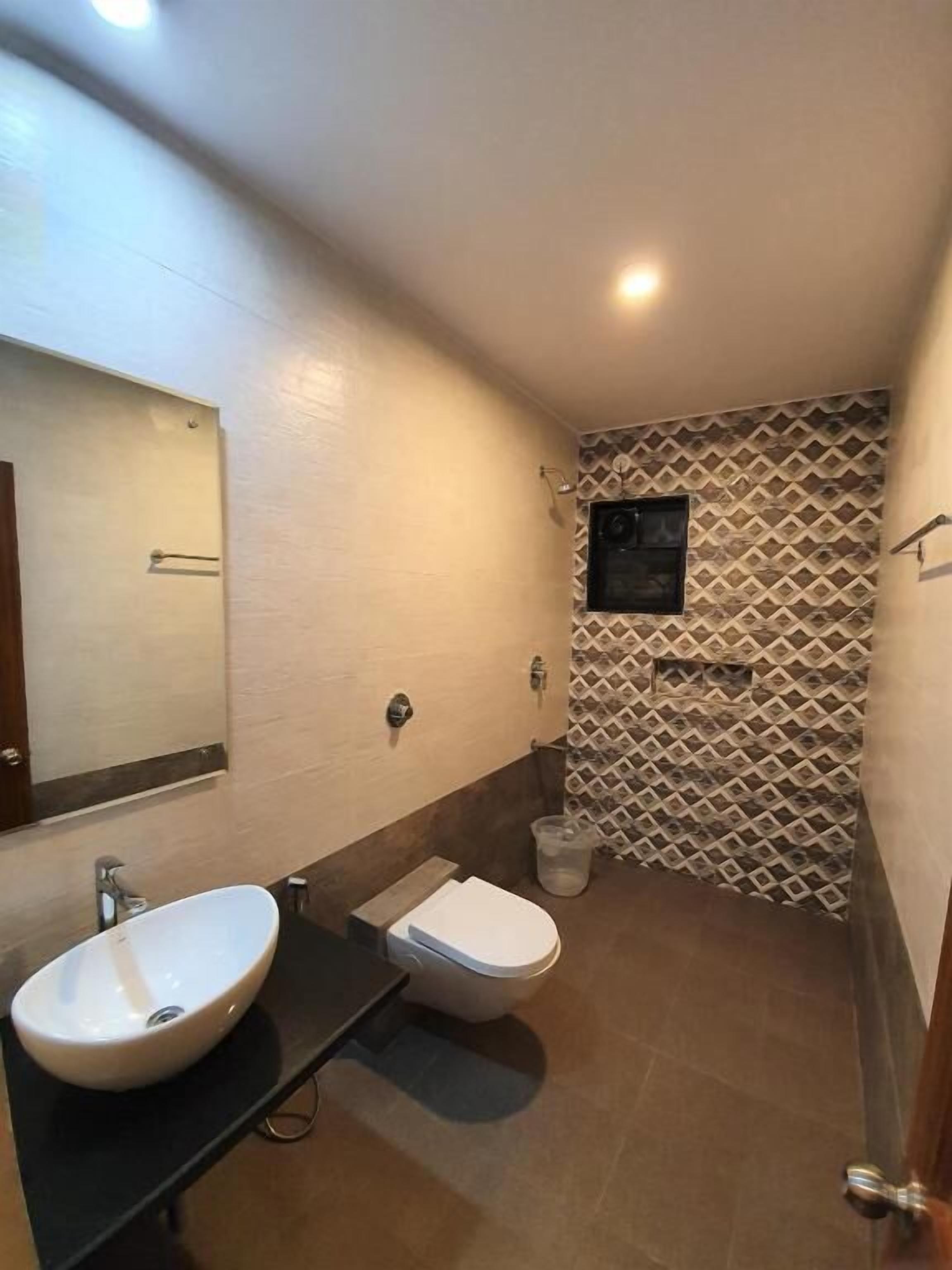 Een badkamer met een wastafel, toilet en spiegel.