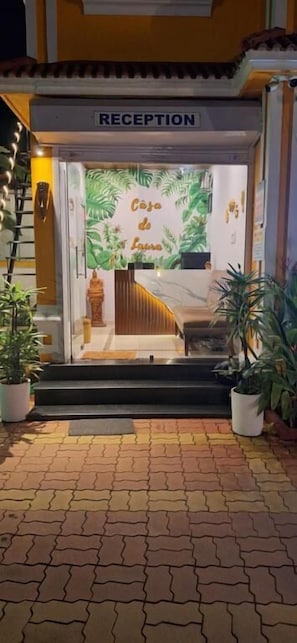 Zona de recepción con un letrero que dice 'RECEPTION' y una pared decorada con motivos de hojas tropicales.