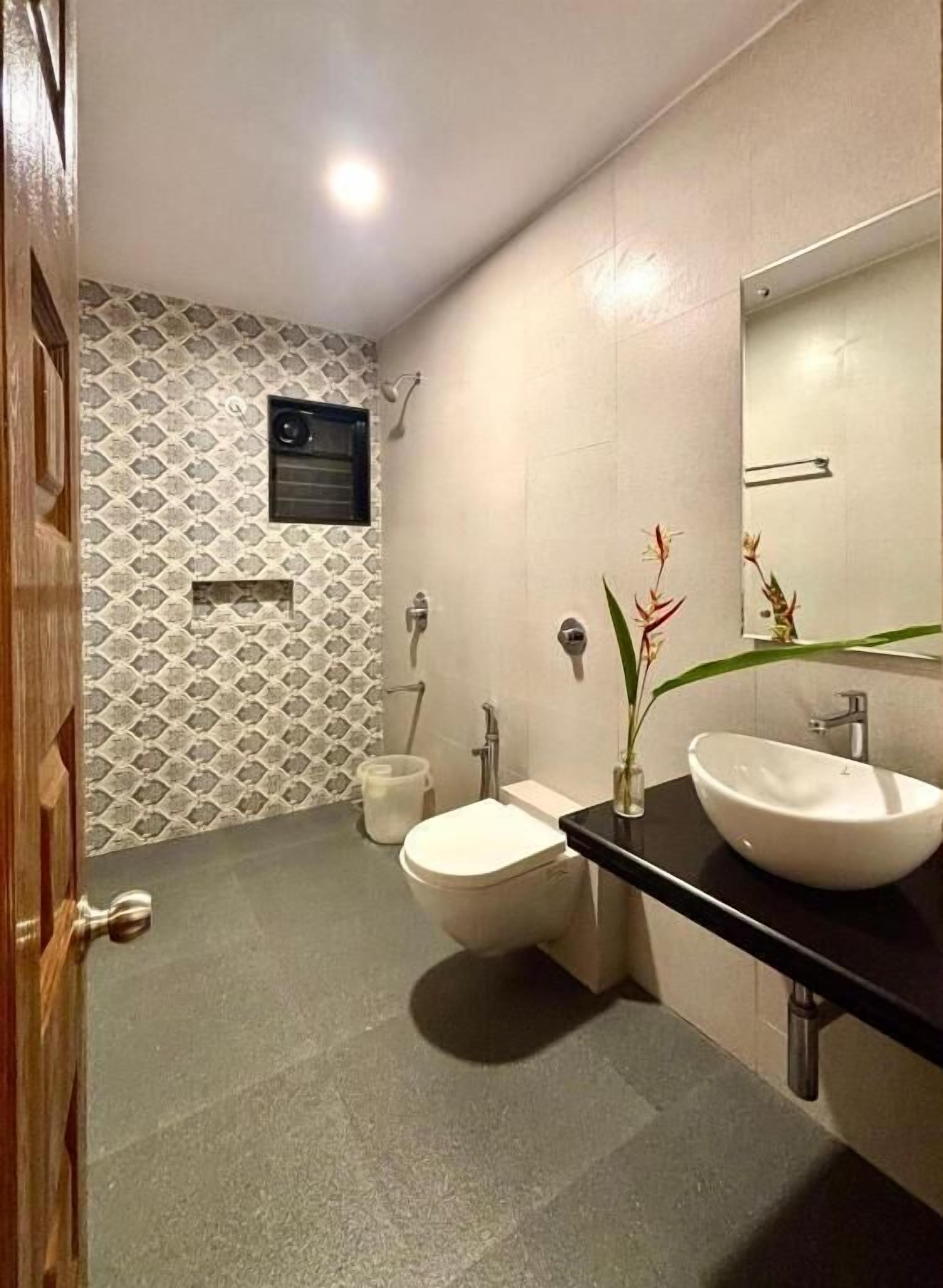 Ein Badezimmer mit Toilette, Waschbecken, Spiegel und einem kleinen Fenster.