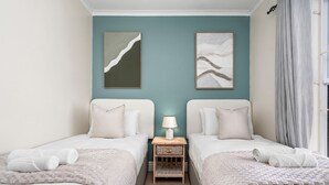 A twin room with two beds, a nightstand with a lamp, and artwork on the walls. - Sangrove Residence (Cape Town)